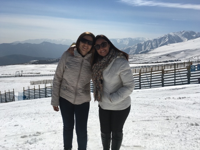 Foto tirada no alto da montanha, eu e minha mãe em pé com neve a todo redor e céu azul
