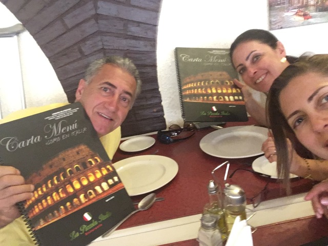 Eu e meus pais sentados na mesa do restaurante italiano