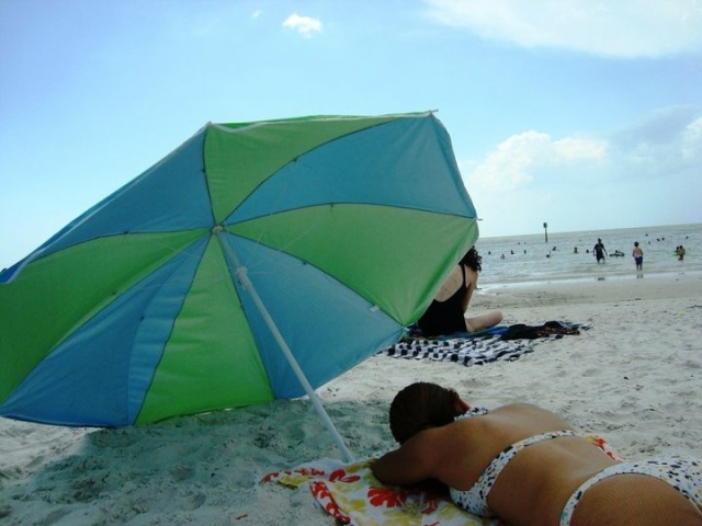 Aparece um grande guarda-sol, e parte do meu corpo deitada na praia